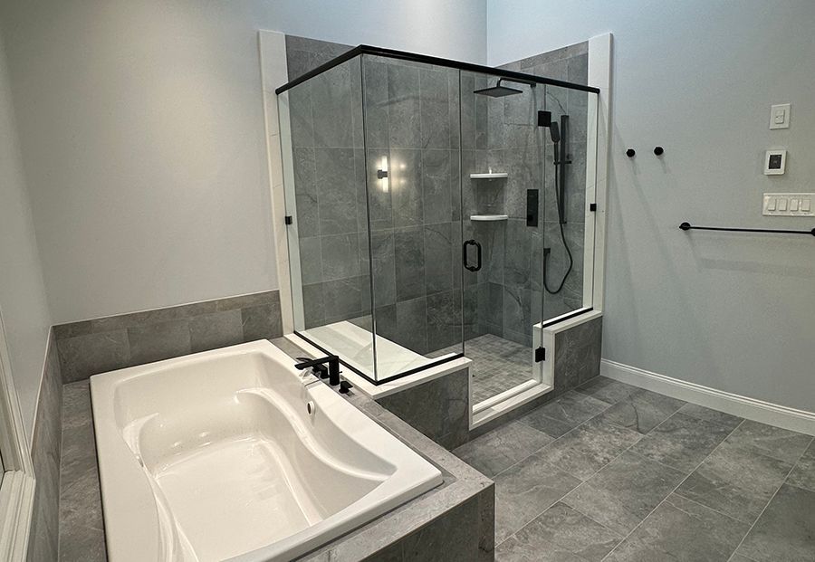 Gray tile bathroom remodel with soaking tub and glass-enclosed shower