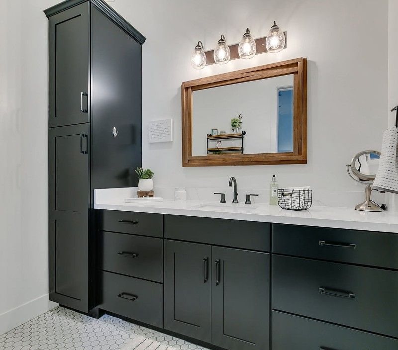 Bathroom with dark green vanity and wood-framed mirror