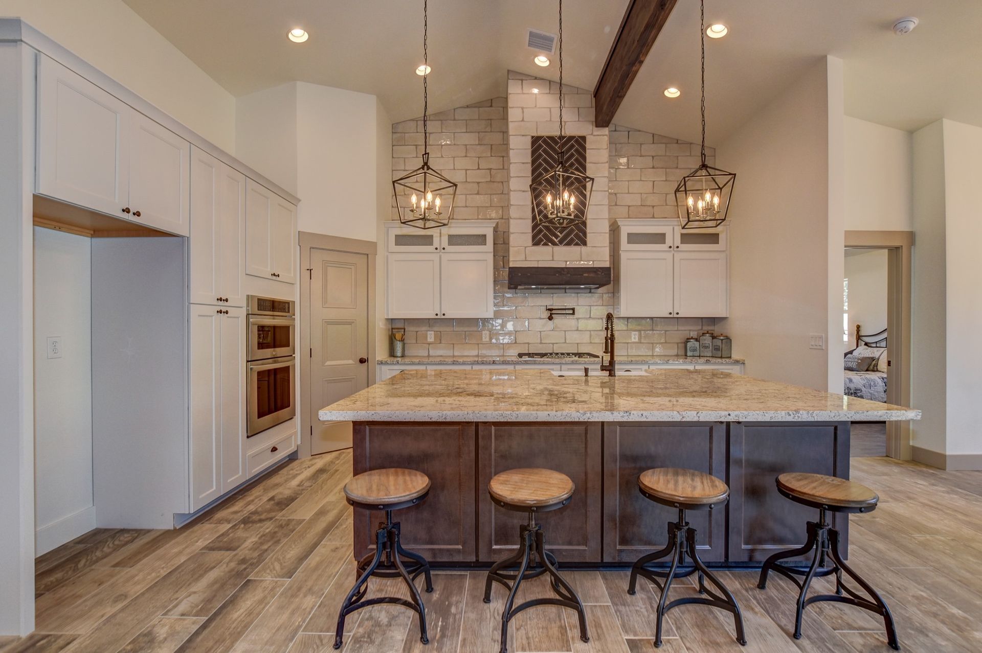 Kitchen remodel with exposed beam, stone island, and lantern pendants