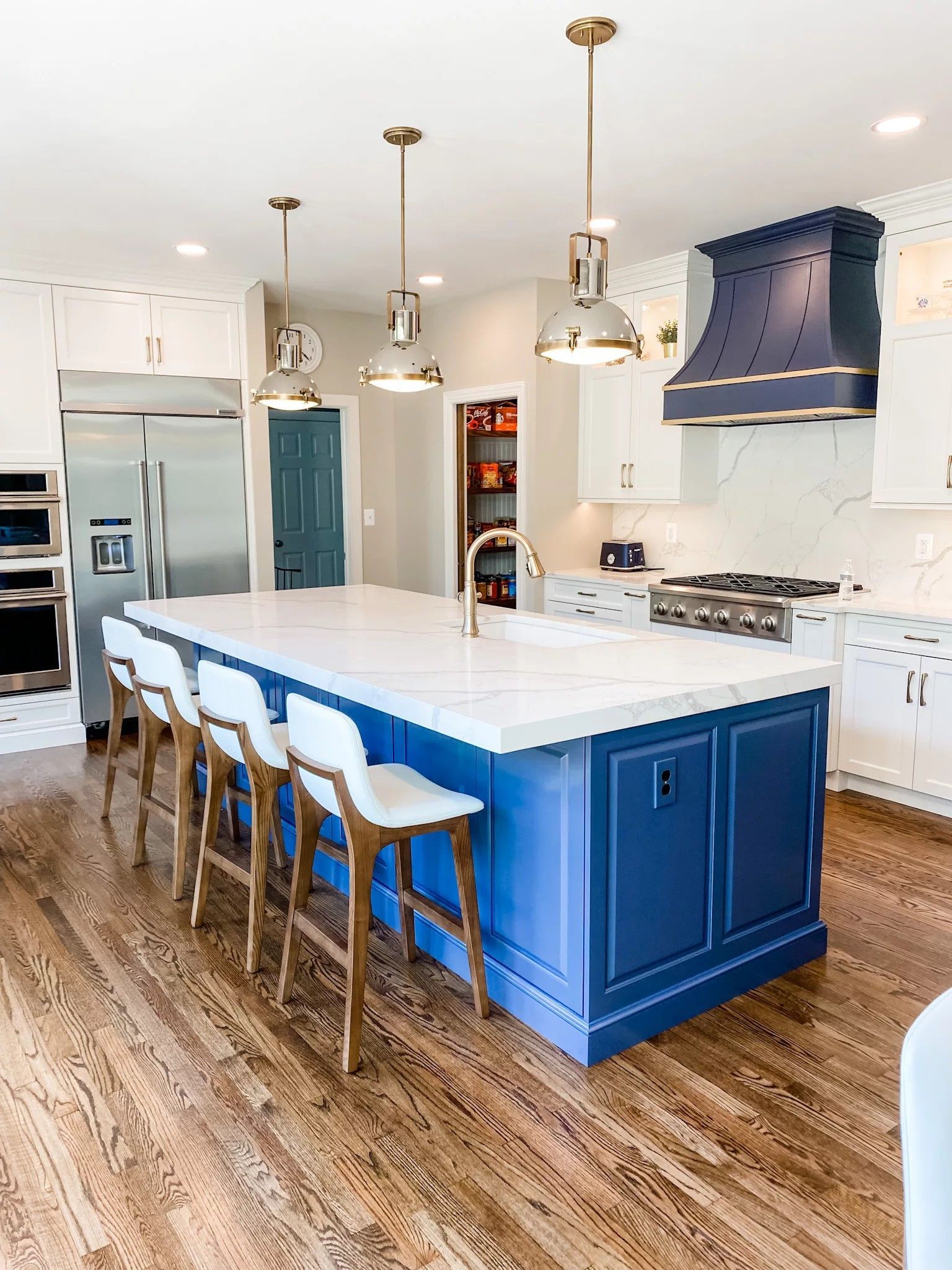 Remodeled Raleigh kitchen with navy island, quartz countertops, and brass pendant lighting
